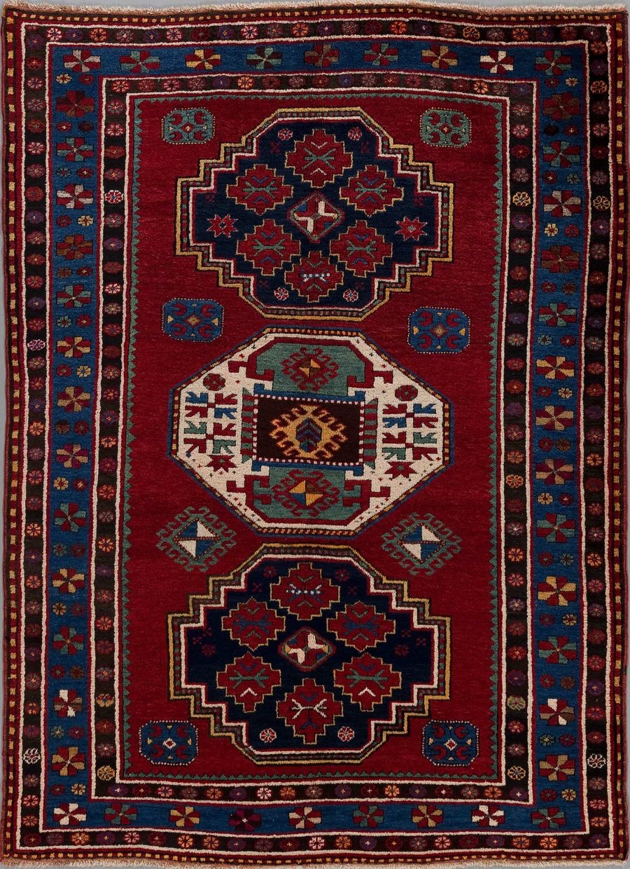 Traditioneller handgeknüpfter Teppich mit komplexem geometrischen Muster in Rot-, Blau-, Beige- und Cremetönen mit dekorativen Bordüren.