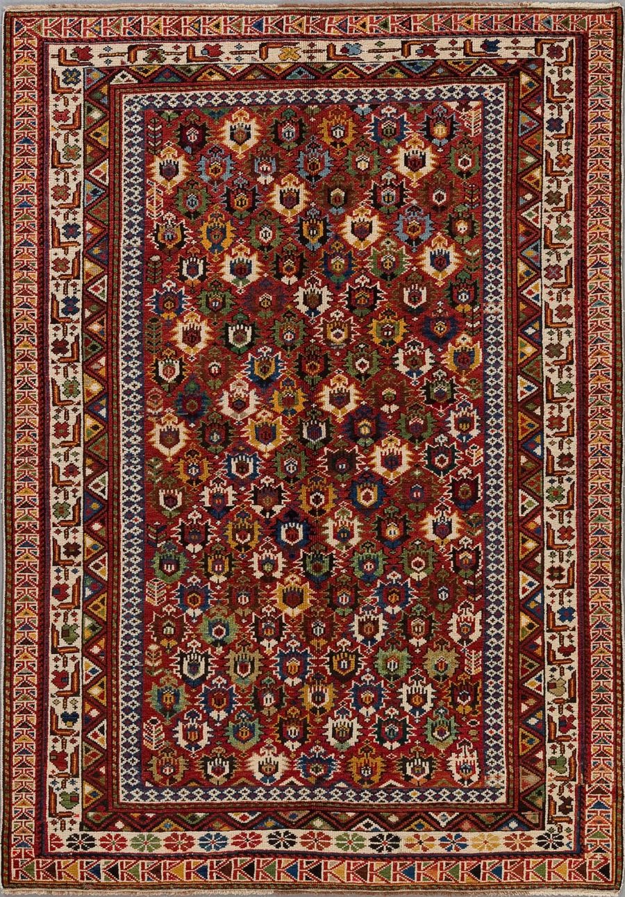 Detailreicher handgewebter Teppich mit komplexen Mustern und vielfältiger Farbpalette, bestehend aus Rottönen, Blau, Weiß und Akzenten in Grün und Gelb, umrahmt von mehrfachen Bordüren mit geometrischen und floralen Motiven.