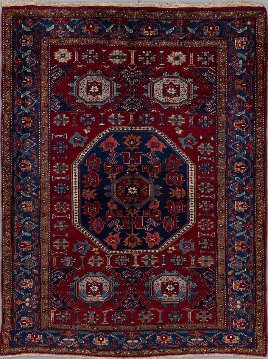 Detailreiche Aufnahme eines persischen Teppichs mit komplexem Muster in primär roten, blauen und cremefarbenen Tönen, umgeben von mehreren verzierten Bordüren.