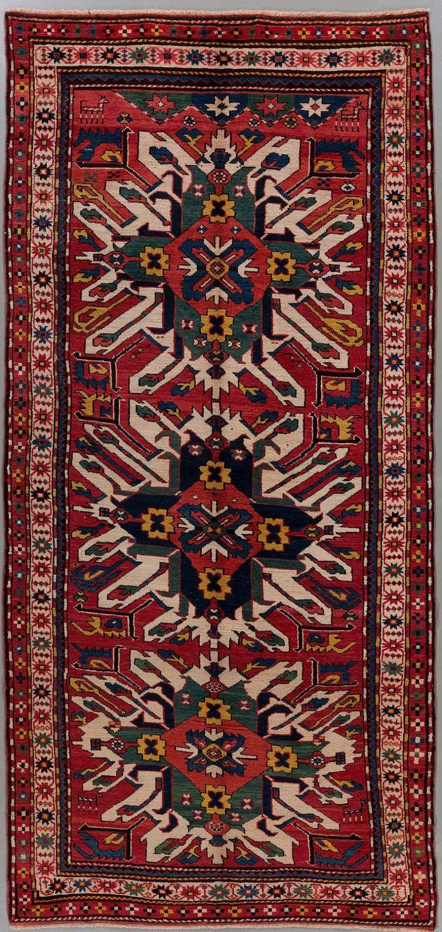 Handgeknüpfter orientalischer Teppich mit komplexem geometrischem Muster und mehreren Bordüren in Rot-, Blau-, Grün- und Cremetönen.