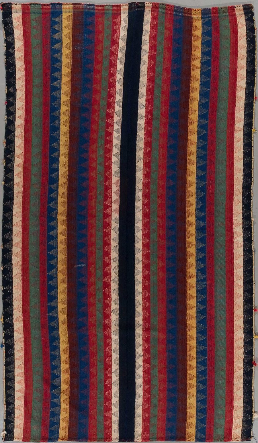 Antikes, gestreiftes Textil mit verschiedenen breiten Streifen in den Farben Rot, Blau, Grün und Beige auf schwarzem Hintergrund, rustikal gewebt mit sichtbaren Verschleißspuren.