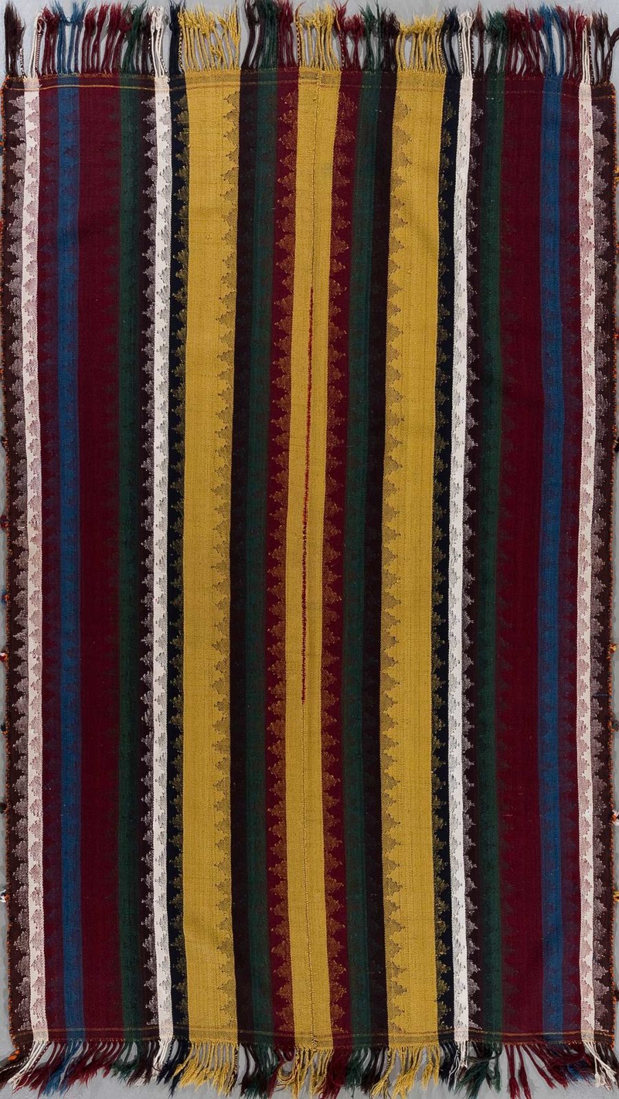 Vertikal gestreifter handgewebter Teppich in den Farben Rot, Blau, Gelb und Grün mit Fransen an den kurzen Enden und traditionellen Mustern.