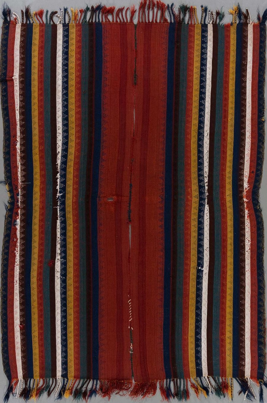 Texturiertes, gemustertes Gewebe mit vertikalen Streifen in verschiedenen Farbtönen wie Rot, Grün, Gelb und Weiß, mit sichtbarer Abnutzung und Fransen an den Rändern.