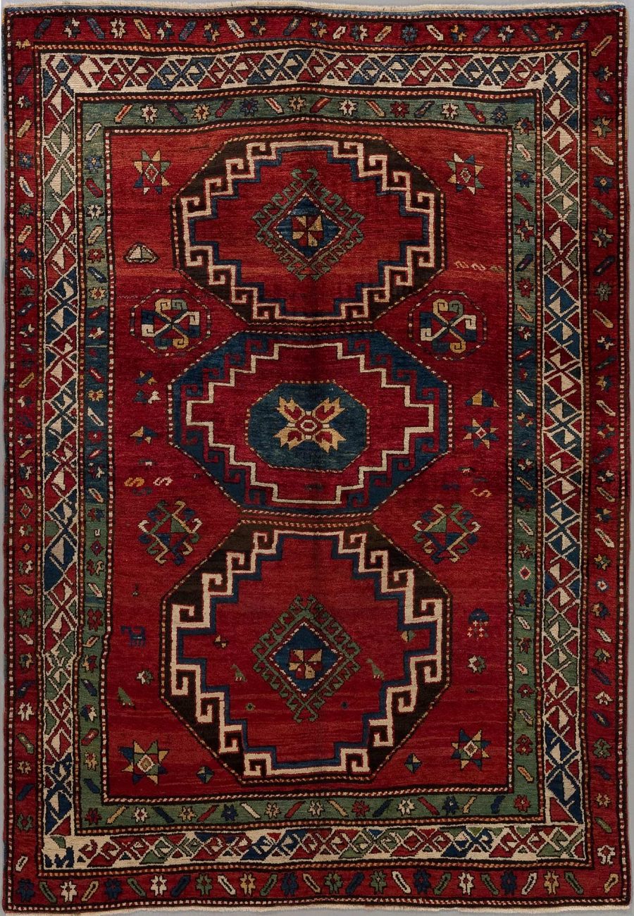 Traditioneller handgeknüpfter Teppich mit symmetrischem Muster in Rot-, Blau- und Beigetönen, umgeben von mehreren dekorativen Bordüren.