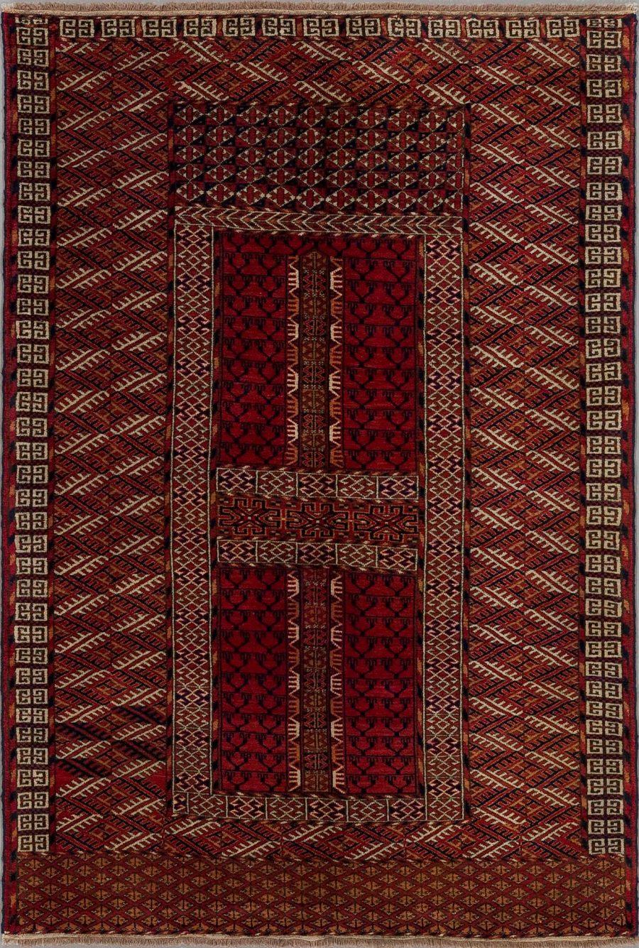 Traditioneller roter Teppich mit komplexem geometrischem Muster und zentralen Medaillons, umgeben von einem breiten dekorativen Rand.