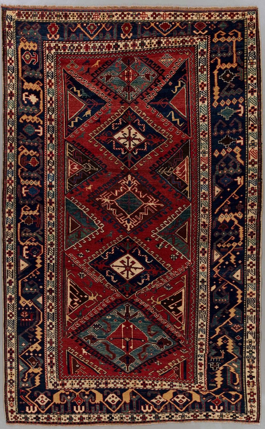 Antiker handgewebter orientalischer Teppich mit komplexen geometrischen Mustern und Bordüren in roten, blauen und beige Tönen.