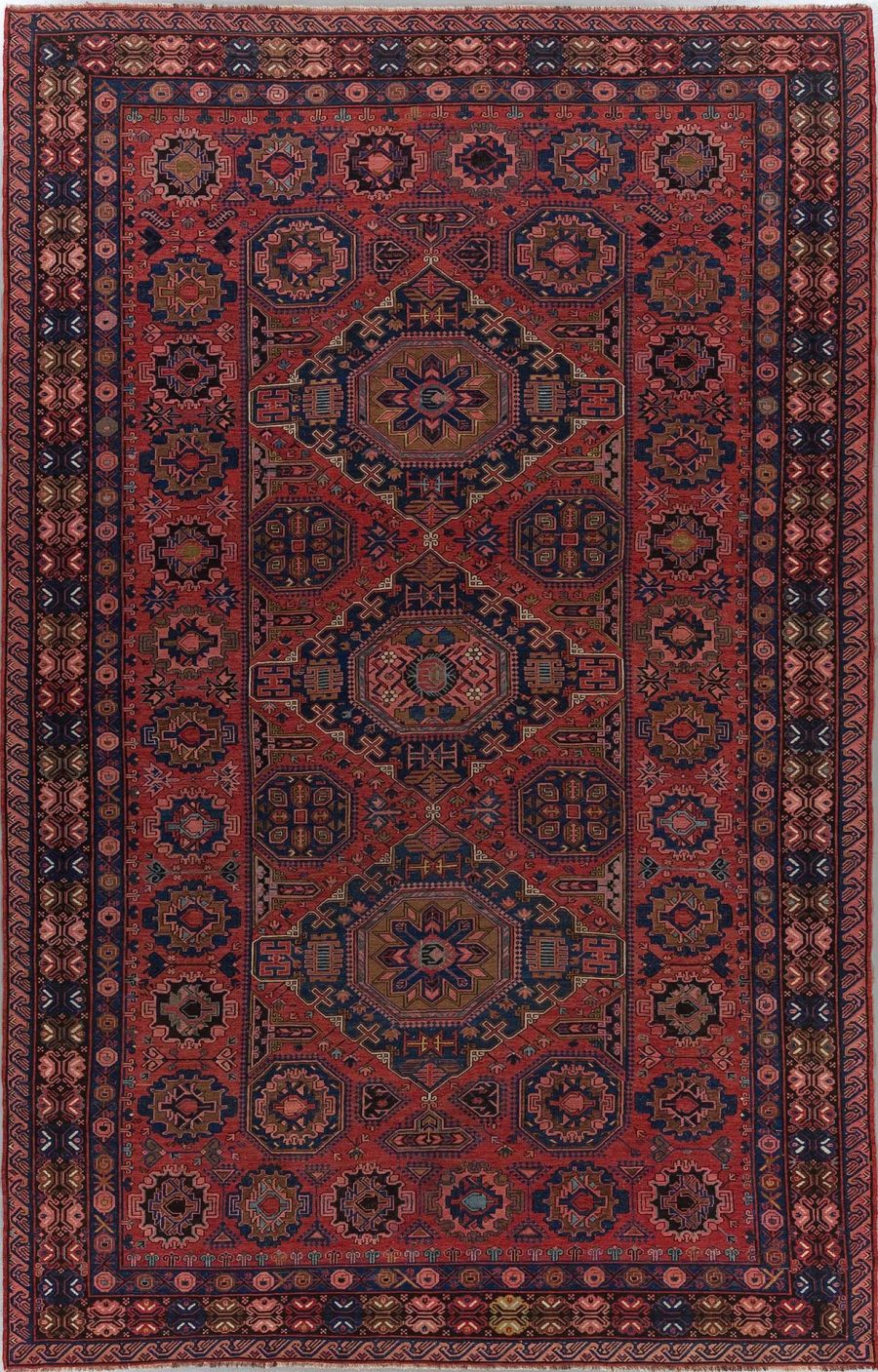 Traditioneller handgeknüpfter Teppich mit komplexen geometrischen Mustern und Medaillons in Rot-, Blau- und Beigetönen, umgeben von mehrfachen Bordüren.