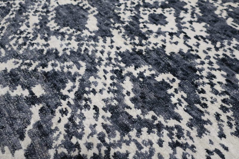Nahaufnahme eines gemusterten Teppichs mit einem abstrakten Design in Weiß und verschiedenen Blautönen.