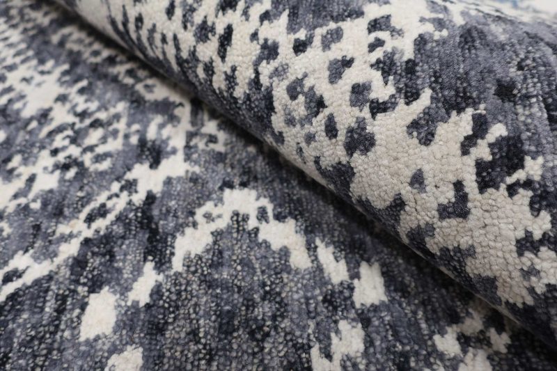 Nahaufnahme eines gemusterten Teppichs mit einem abstrakten Design in Weiß und verschiedenen Blautönen.