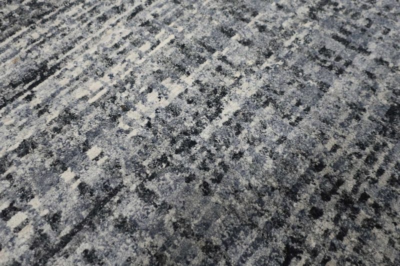 Strukturierte Nahaufnahme eines gemusterten Teppichs mit grau-schwarzen und weißen Farbnuancen.