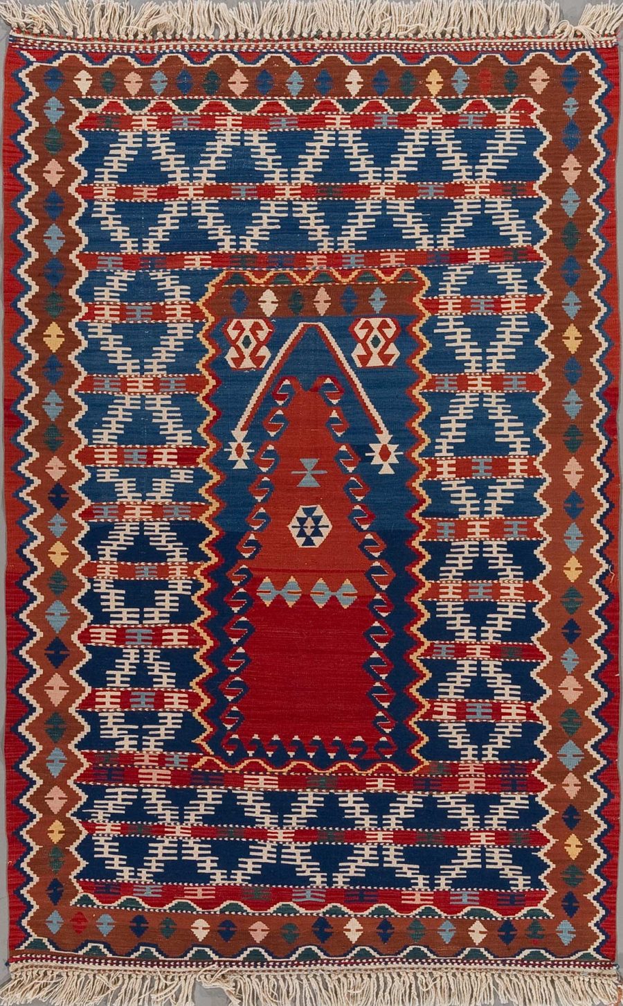 Handgeknüpfter Teppich mit detailreichen Mustern in Rot, Blau, Beige und Braun, mit Fransen an den Enden.