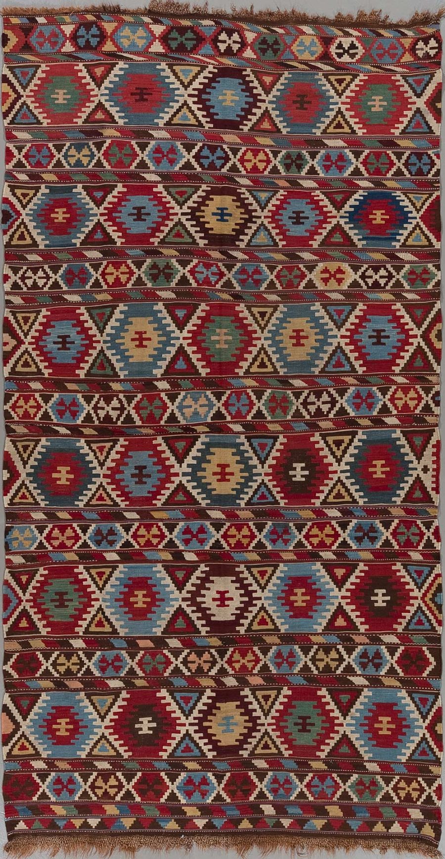 Traditioneller handgewebter Teppich mit geometrischen Mustern in Rot-, Blau-, Braun- und Beigetönen.