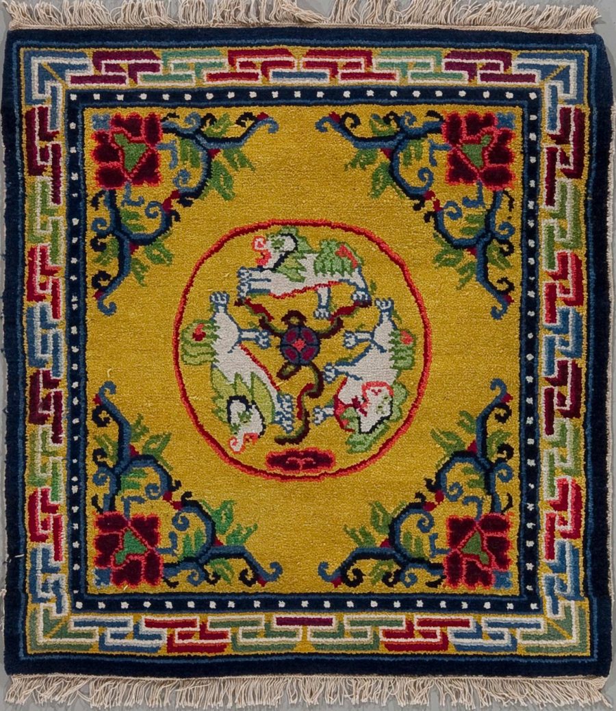 Handgeknüpfter Teppich mit geometrischem und floralem Muster, zentrales Medaillon mit Tieraufstellung und pflanzlichen Elementen, umgeben von dunkelblauem Rand mit sich wiederholenden Mustern und Fransen an den Enden.