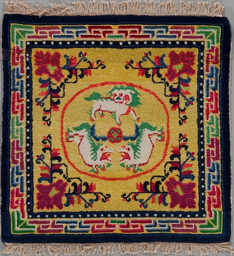 Handgeknüpfter Teppich mit zentralem gelben Medaillon, flankiert von zwei spiegelbildlichen weißen Drachen und roten, blauen sowie grünen Verzierungen, umgeben von einem blumenartigen Muster und einer geometrischen Bordüre in Dunkelblau, Rot, Weiß und Grün.
