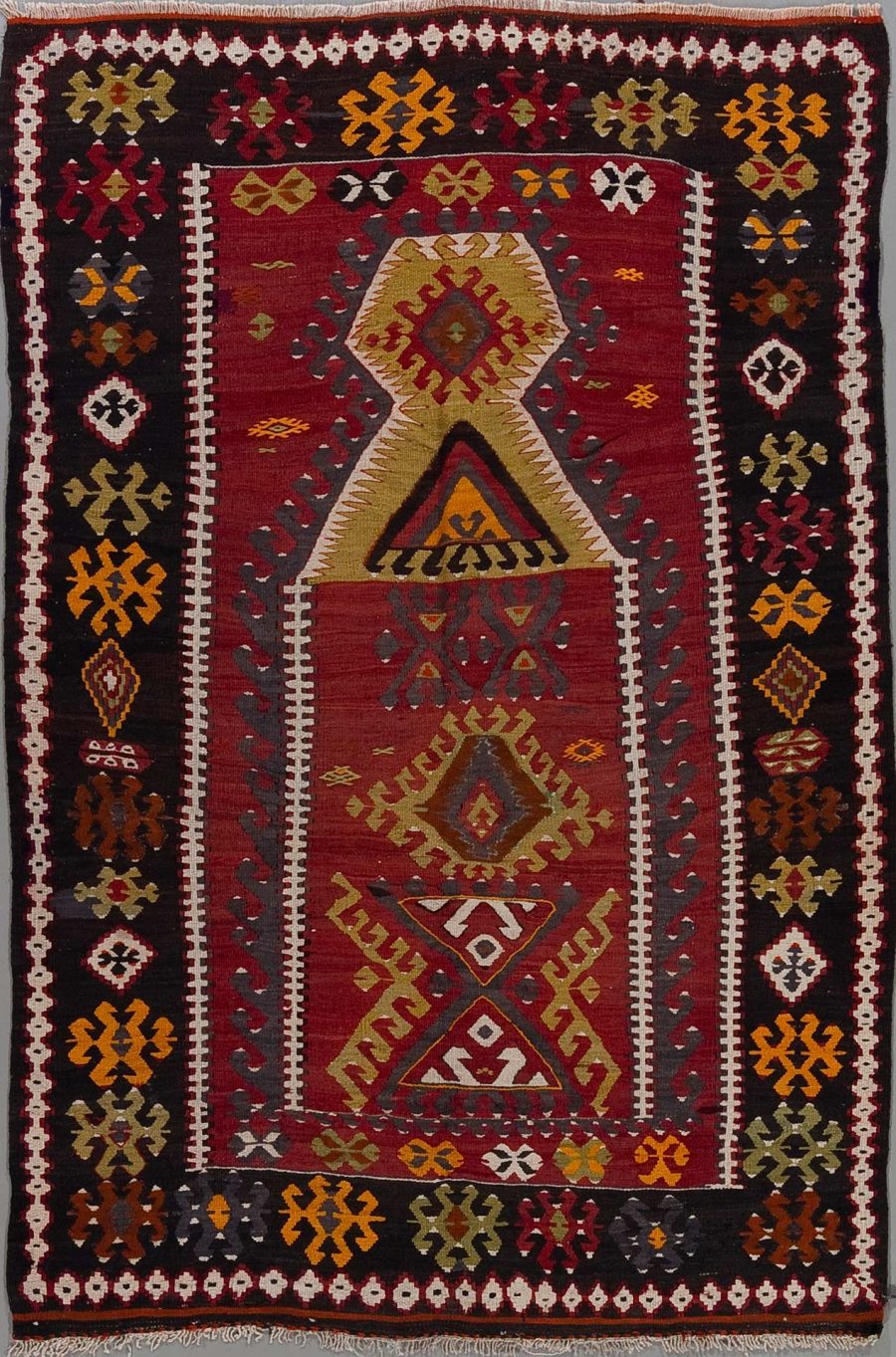 Handgewebter Teppich mit traditionellen Mustern in Rot-, Gelb-, Weiß- und Schwarztönen, zentrales geometrisches Design umgeben von dekorativen Bordüren.