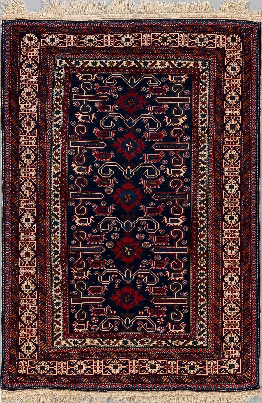 Handgeknüpfter orientalischer Teppich mit detailliertem Muster in dunkelblau, rot und beige auf einem schwarzem Hintergrund, umgeben von geometrischen Rändern und Fransen an den Enden.