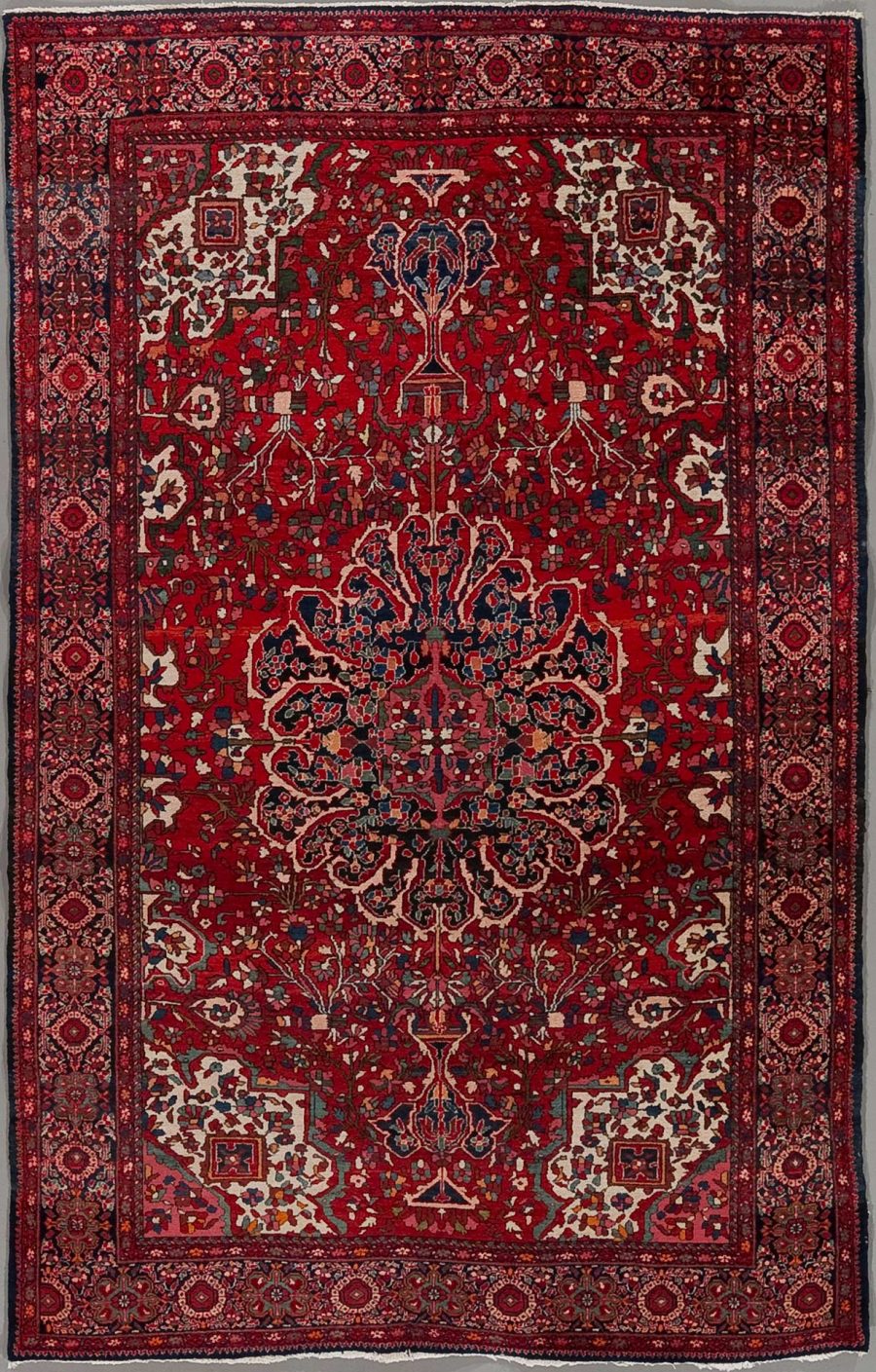 Traditioneller orientalischer Teppich mit komplexem, symmetrischem Muster in vorrangig roten und blauen Tönen, umgeben von mehreren dekorativen Rändern.