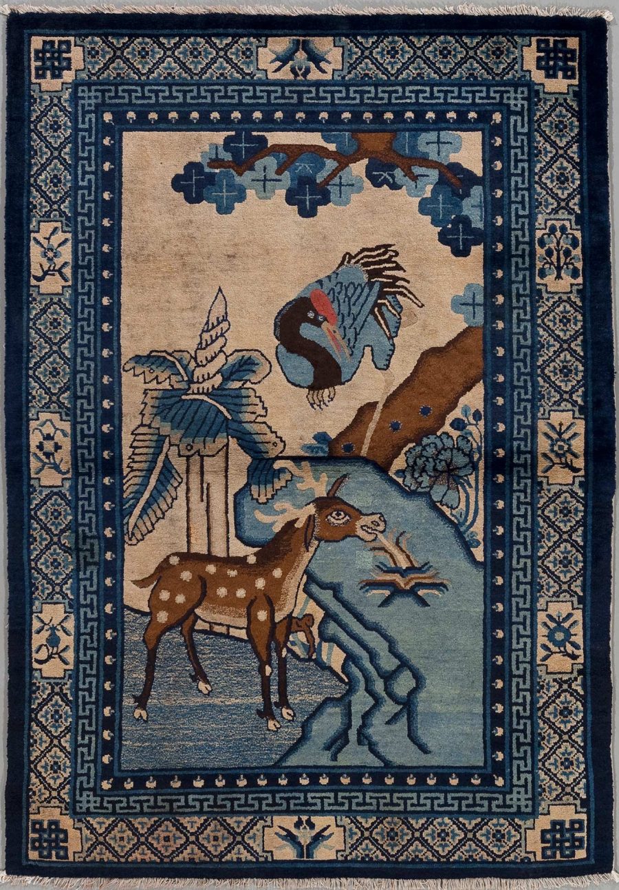 Antiker Wandteppich mit aufwendigem Muster und Abbildungen eines Rehs und eines Kranichs in einem Waldmotiv, umrandet von einem dekorativen geometrischen Rand in Blau- und Beigetönen.