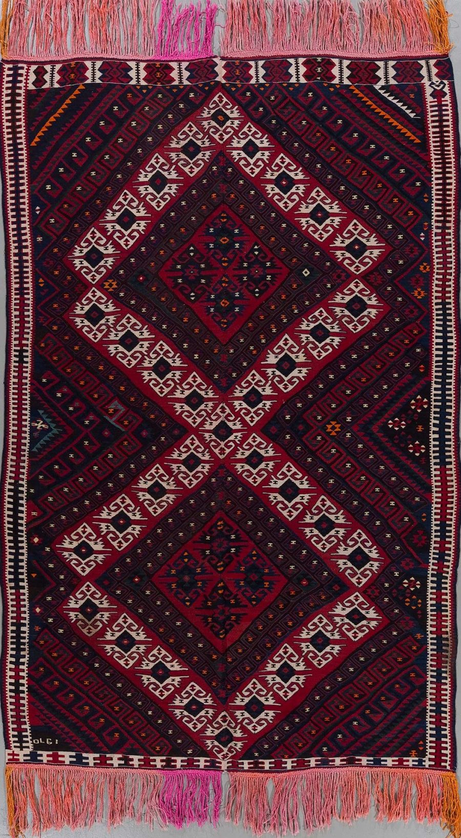 Handgewebter Teppich mit komplexem, symmetrischem Muster in Rot-, Schwarz- und Weißtönen sowie Fransen an den Enden.