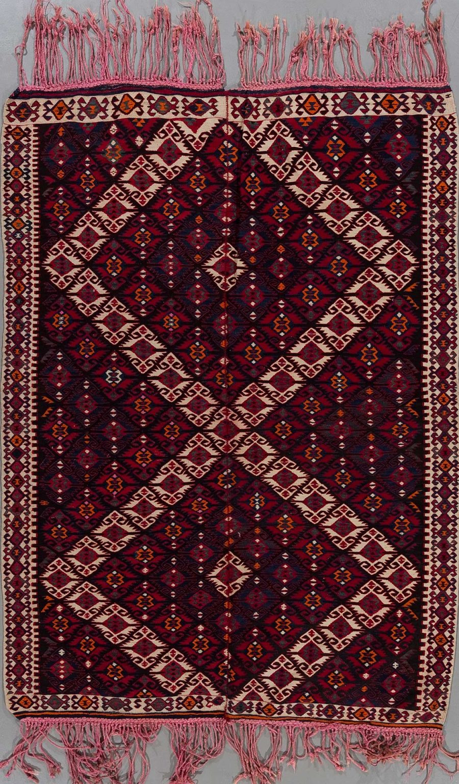 Traditioneller handgewebter Teppich mit komplexen geometrischen Mustern in Rot-, Schwarz-, Weiß- und Orangetönen, Fransen an beiden Enden