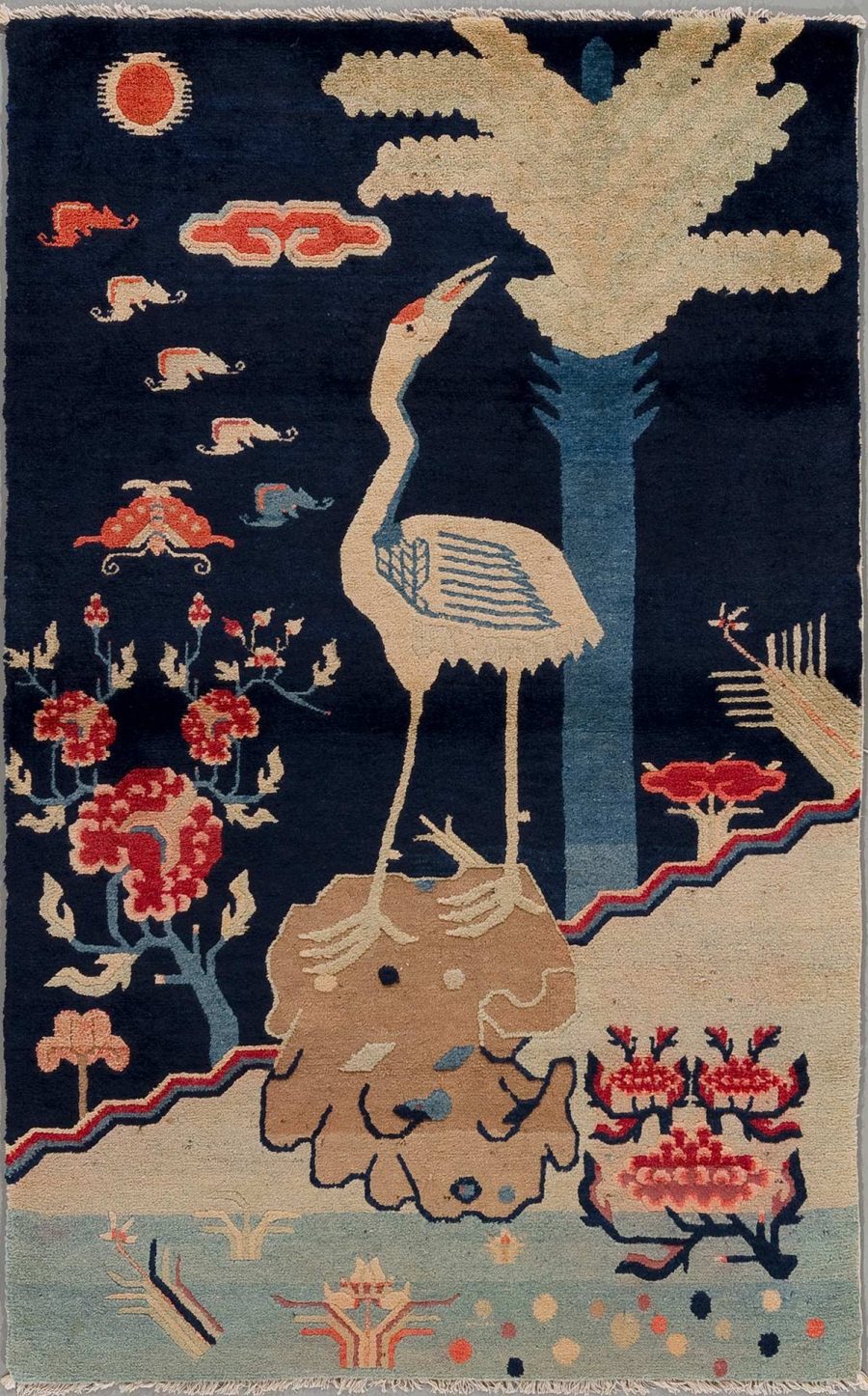 Handgewebter Teppich mit folkloristischem Muster, darstellend einen Storch unter einem Baum, umgeben von Wolken, Sonne, laufenden Elefanten und Blumen. Farben sind hauptsächlich Dunkelblau, Beige und Rottöne.
