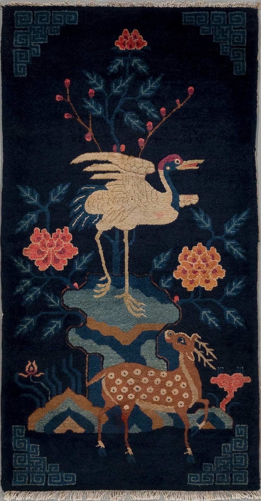 Asiatischer Stil Wandteppich mit der Darstellung eines Kranichs auf einem Hirsch neben Pfingstrosen und geometrischen Mustern auf dunkelblauem Hintergrund.