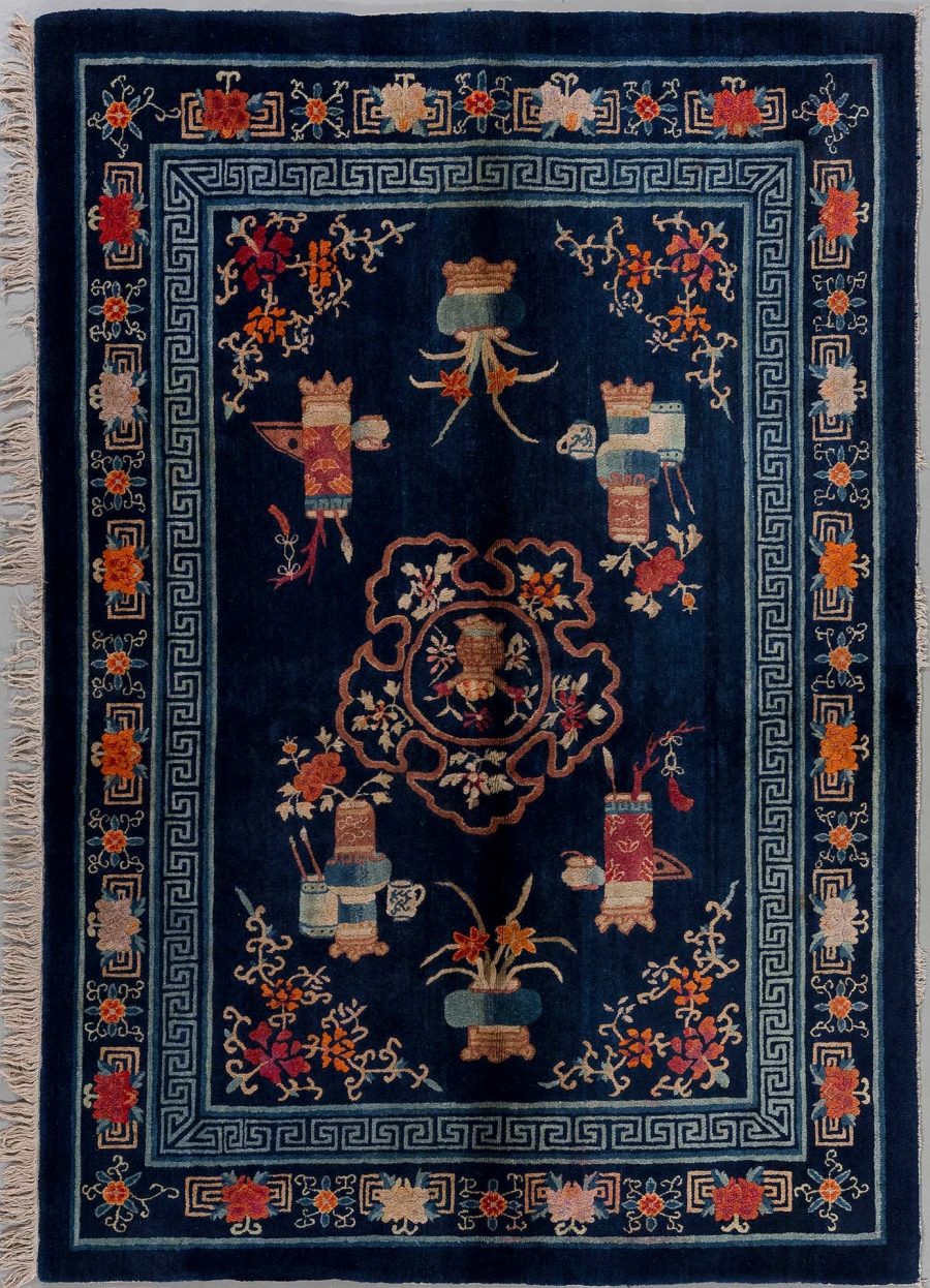 Detaillierter handgeknüpfter Teppich mit traditionellen chinesischen Motiven, darunter Vasen und Blumen, in vorherrschend dunkelblauen, orange- und beige-Tönen mit einer Griechischen Schlüsselbordüre sowie Fransen an den kurzen Enden.