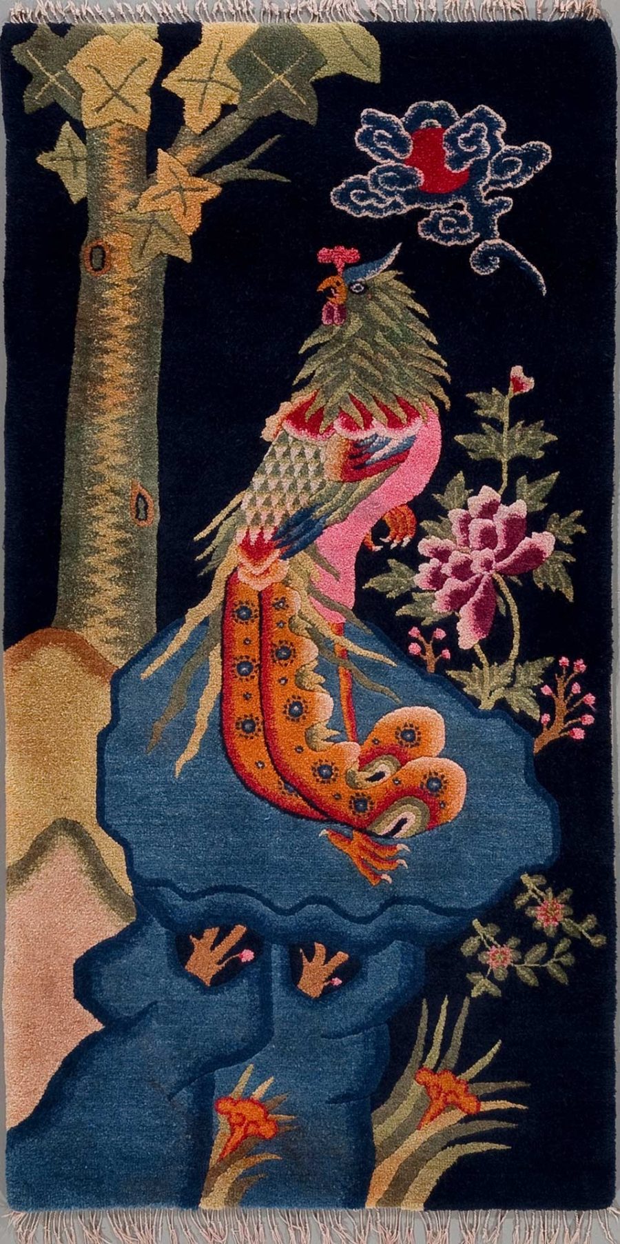 Farbiges Wandteppich-Design mit einem asiatisch anmutenden Drachen in Rottönen mit blauen und gelben Akzenten, der um eine Felsformation gewickelt ist. Darüber eine stilisierte Wolke und umgeben von traditionellen Motiven wie Bäumen und Blumen auf dunklem Hintergrund.