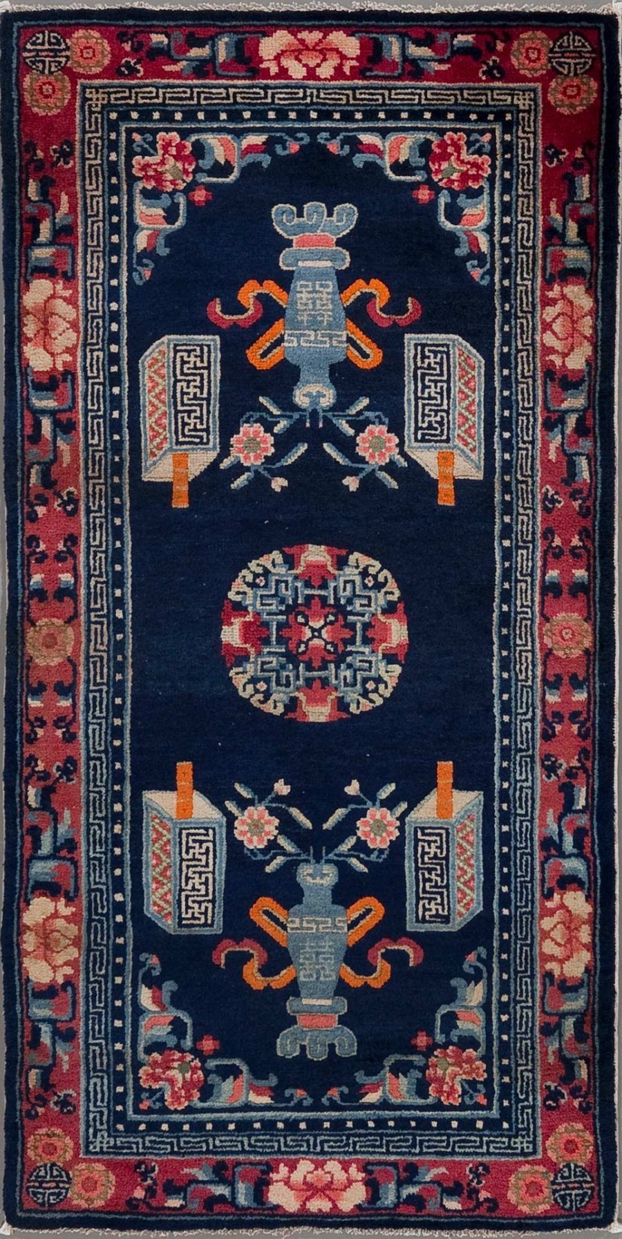 Traditioneller, von Hand gewebter Orientteppich mit dunkelblauem Hintergrund und einem zentralen Medaillon, umgeben von symmetrischen floralen Mustern und Vasenmotiven in Farben wie Rot, Beige und Blau; mit geometrischen Bordüren in Rot und Beige.