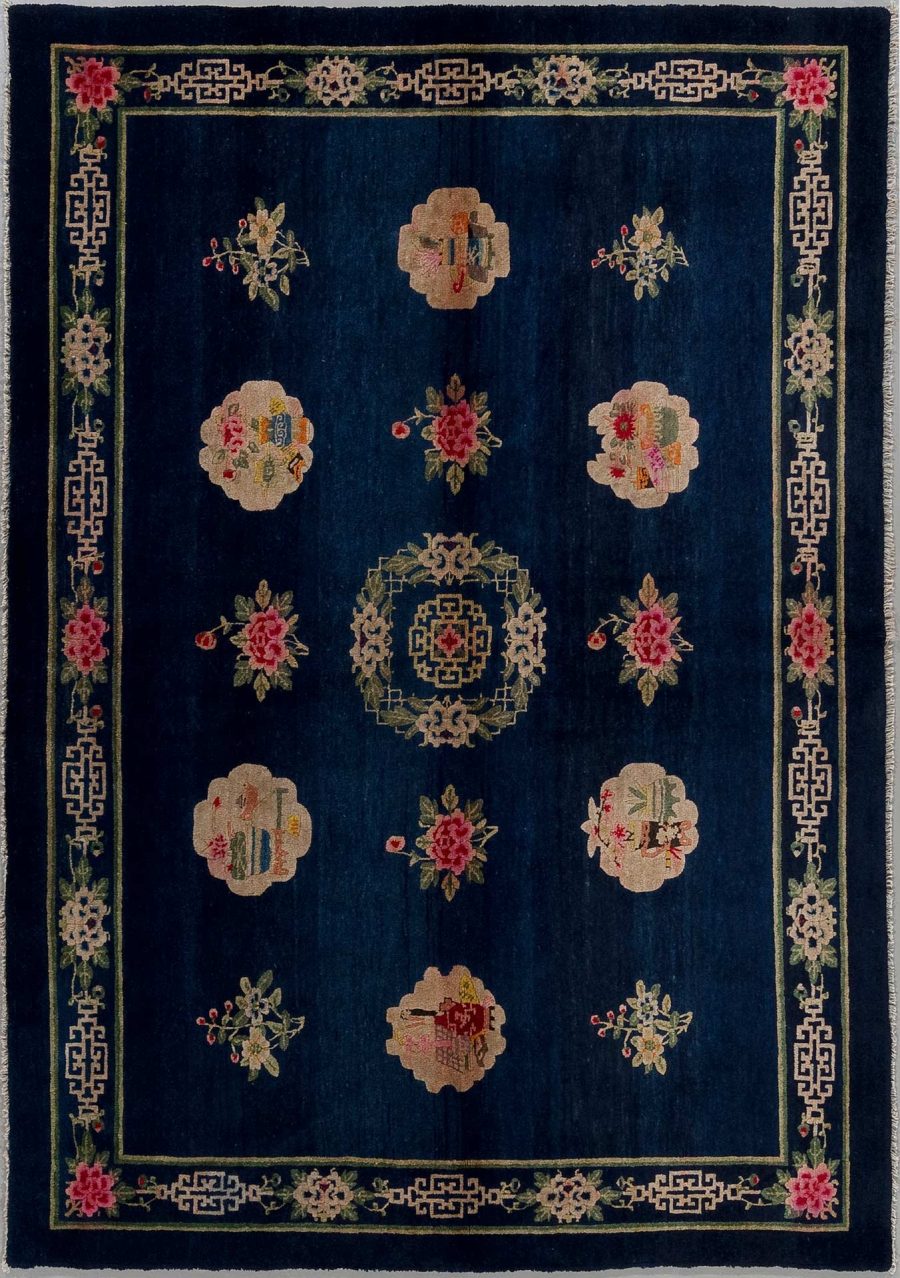 Alt-Text: Traditioneller orientalischer Teppich mit dunkelblauem Grund und einem symmetrischen Muster aus rosafarbenen Blumen und asiatischen Ornamenten in Beige- und Rottönen, umrandet von einer geometrischen Bordüre.
