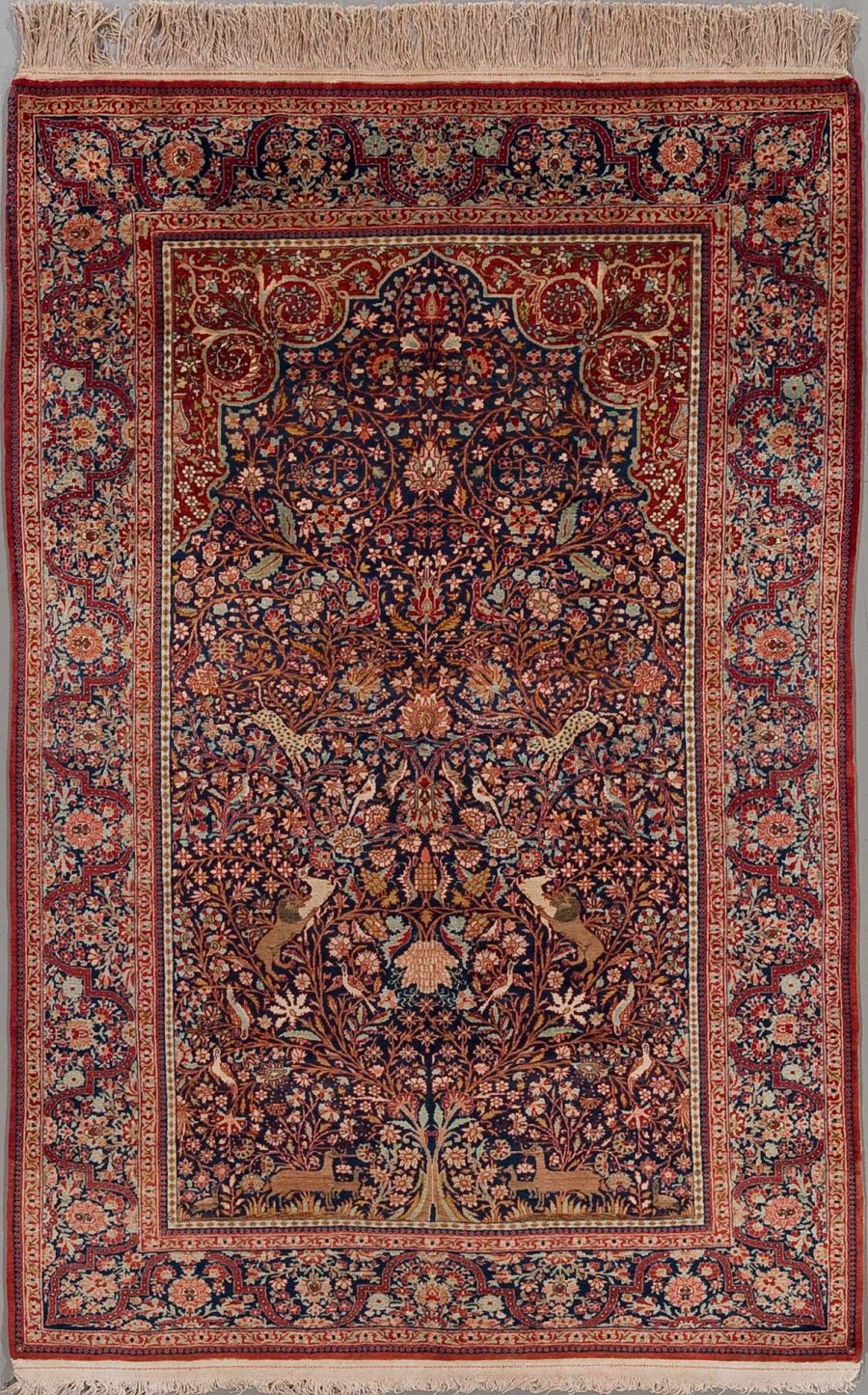 Detailreich geknüpfter persischer Teppich in dunklen und warmen Farben mit komplexen floralen Mustern und zentralem Medaillon auf dunkelblauem Grund, umgeben von Bordüren in Rot- und Beigetönen.