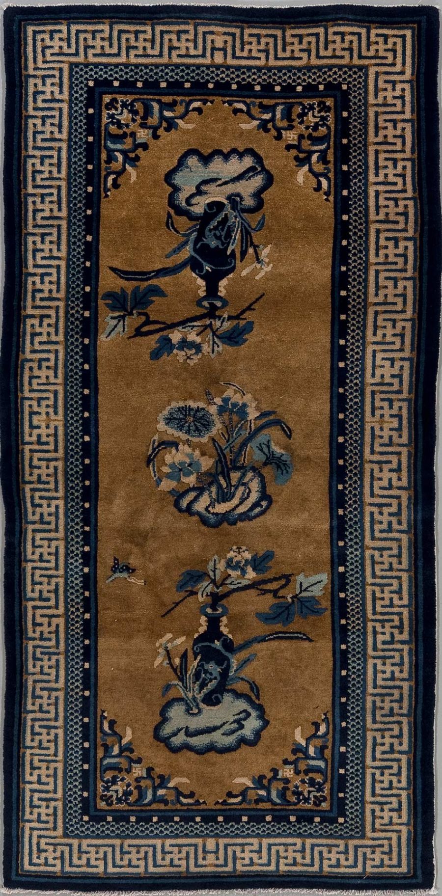Länglicher, handgeknüpfter Teppich mit traditionellem asiatischem Design, hauptsächlich in Gold- und Blautönen. Die Bordüren zeigen ein griechisches Schlüsselmuster und kleinere dekorative Elemente. Das zentrale Motiv beinhaltet stilisierte Blumen und Vasen.
