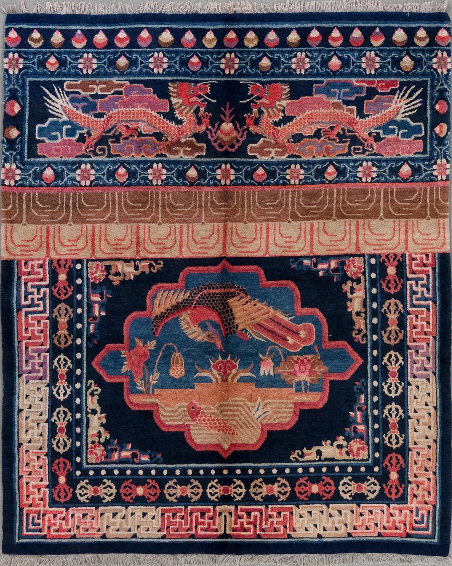 Alt Text: Aufwendig gemusterter Teppich mit einer zentralen Medaillon-Szene, umgeben von Drachen und floralem Design auf dunkelblauem Grund, mit abstrakten Grenzen und Fransen an den Enden.