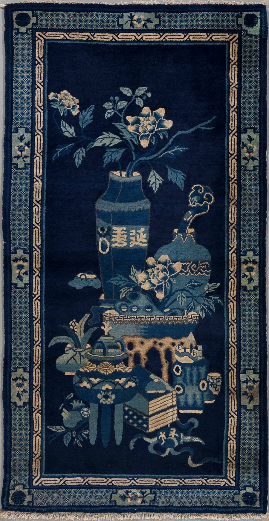 Antiker handgeknüpfter Teppich mit asiatischem Design, zeigt auf dunkelblauem Grund traditionelle Motive wie Vasen, Blumen, Schriftzeichen und dekorative Bordüren.