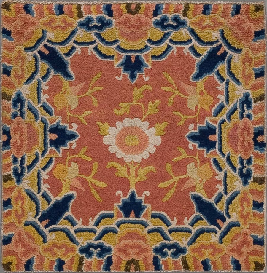 Detaillierte Nahaufnahme eines orientalischen Teppichs mit symmetrischem Blumenmuster in den Farben Terrakotta, Blau, Gelb und Creme.