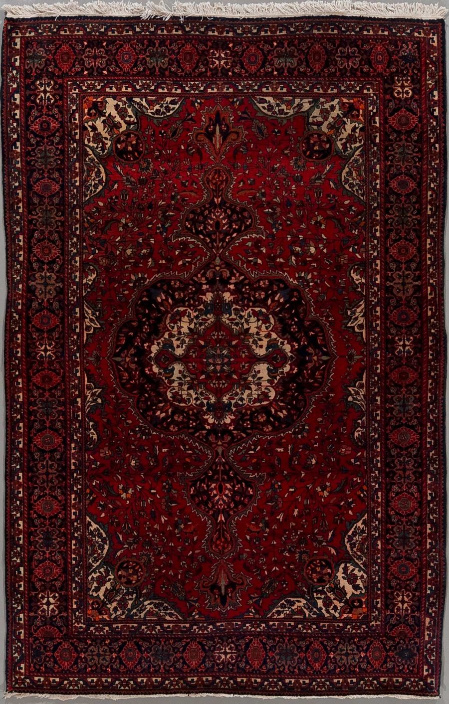 Traditioneller orientalischer Teppich mit komplexem Muster, das florale und geometrische Designs umfasst, in überwiegenden Rottönen mit Akzenten in Blau, Beige und Schwarz.