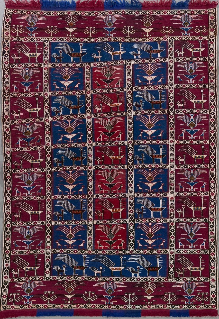 Handgeknüpfter Teppich mit traditionellen Mustern in Rot-, Blau- und Beigetönen mit Fransen an den kurzen Seiten.