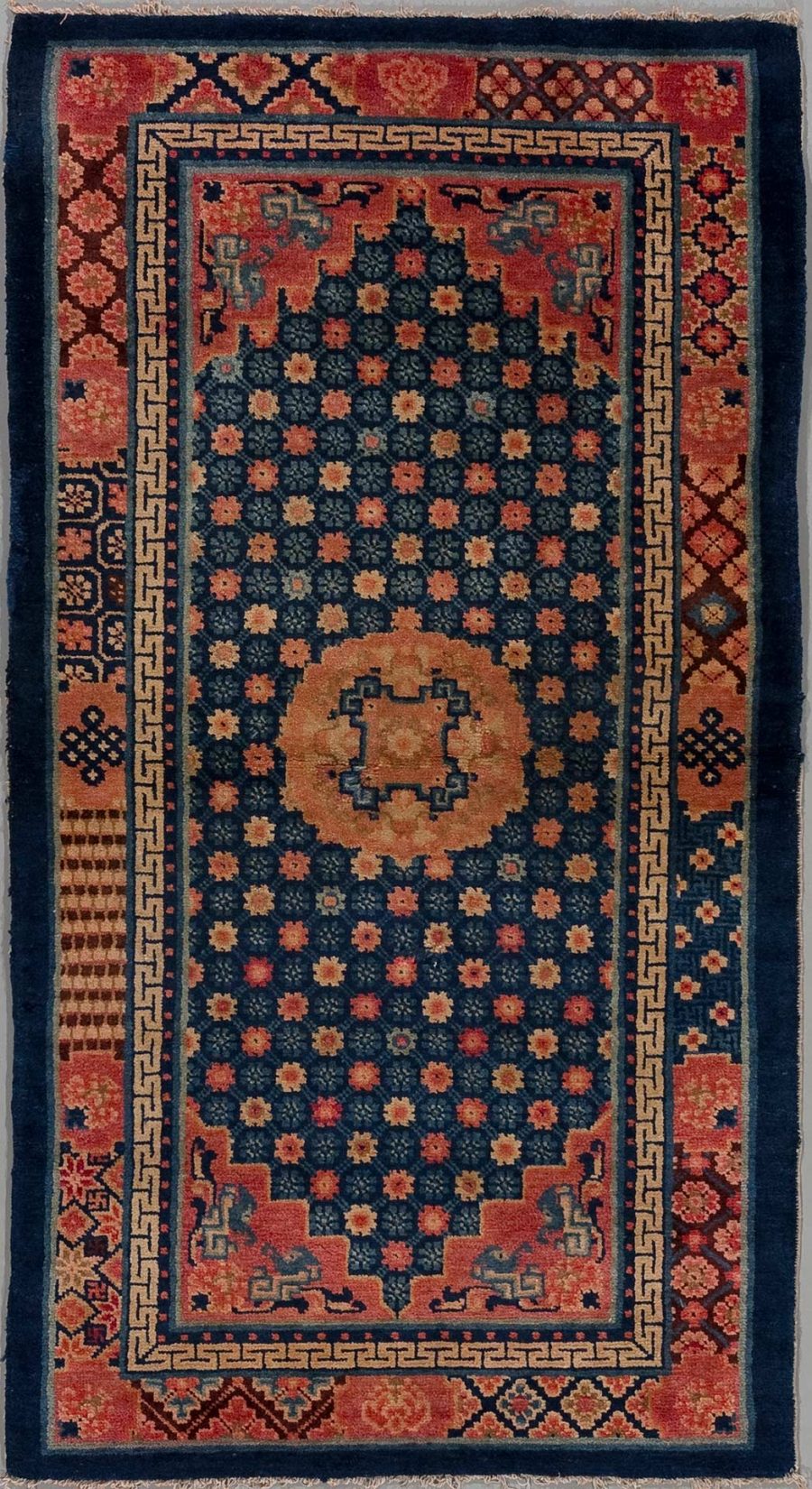 Antiker handgeknüpfter Teppich mit komplexen geometrischen und floralen Mustern in Dunkelblau, Rostrot und Beigetönen, umgeben von mehreren Zierrahmen und zentralem Medaillon.