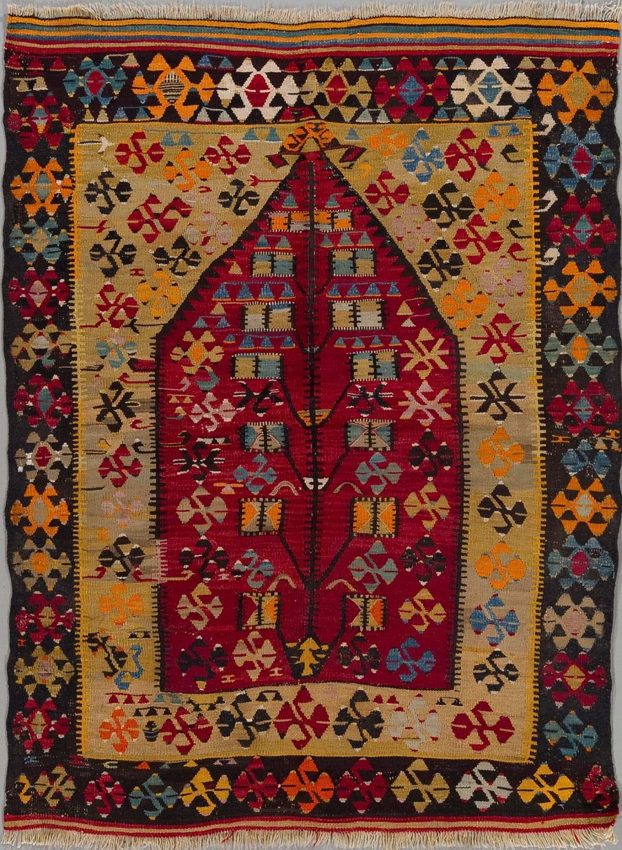 Traditioneller handgewebter Teppich mit komplexen geometrischen Mustern und einem zentralen, diamantförmigen Medaillon in Rot- und Beigetönen, umgeben von vielfältigen Bordüren und Eckmotiven.