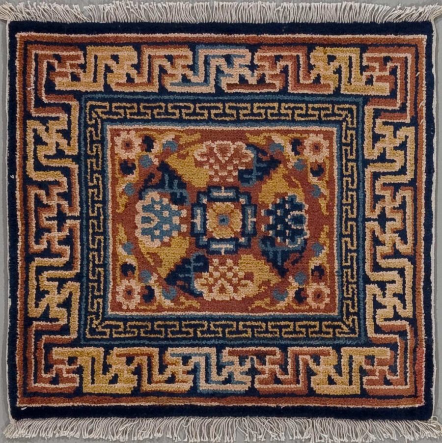Handgewebter Teppich mit detailliertem geometrischem Muster in Blau, Beige, und Terrakotta, umgeben von einer dreifachen Bordüre und Fransen an den Enden.