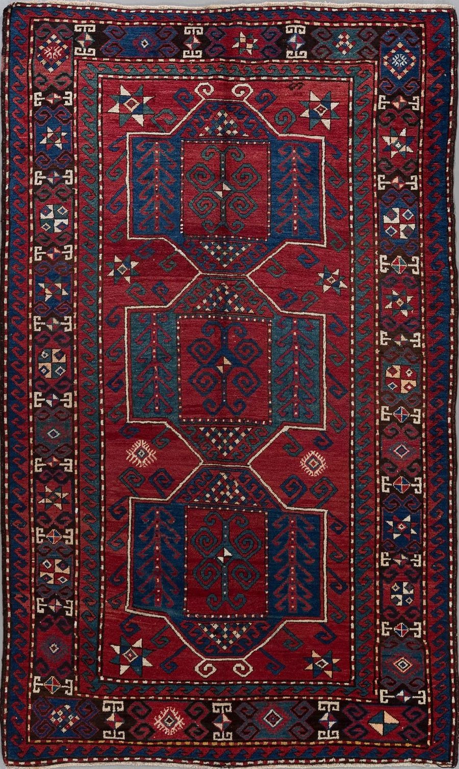 Traditioneller orientalischer Teppich mit komplexem Muster in Rot-, Blau- und Beigetönen, umgeben von mehreren dekorativen Bordüren mit geometrischen und pflanzlichen Motiven.