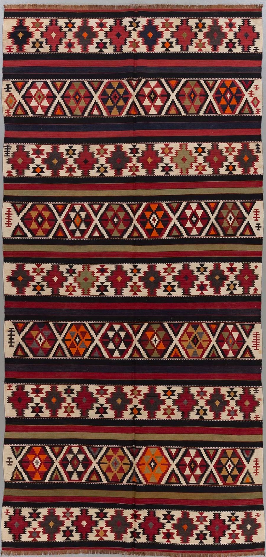 Traditioneller handgewebter Teppich mit komplexen geometrischen Mustern in überwiegend roten, schwarzen, weißen und orangefarbenen Tönen.