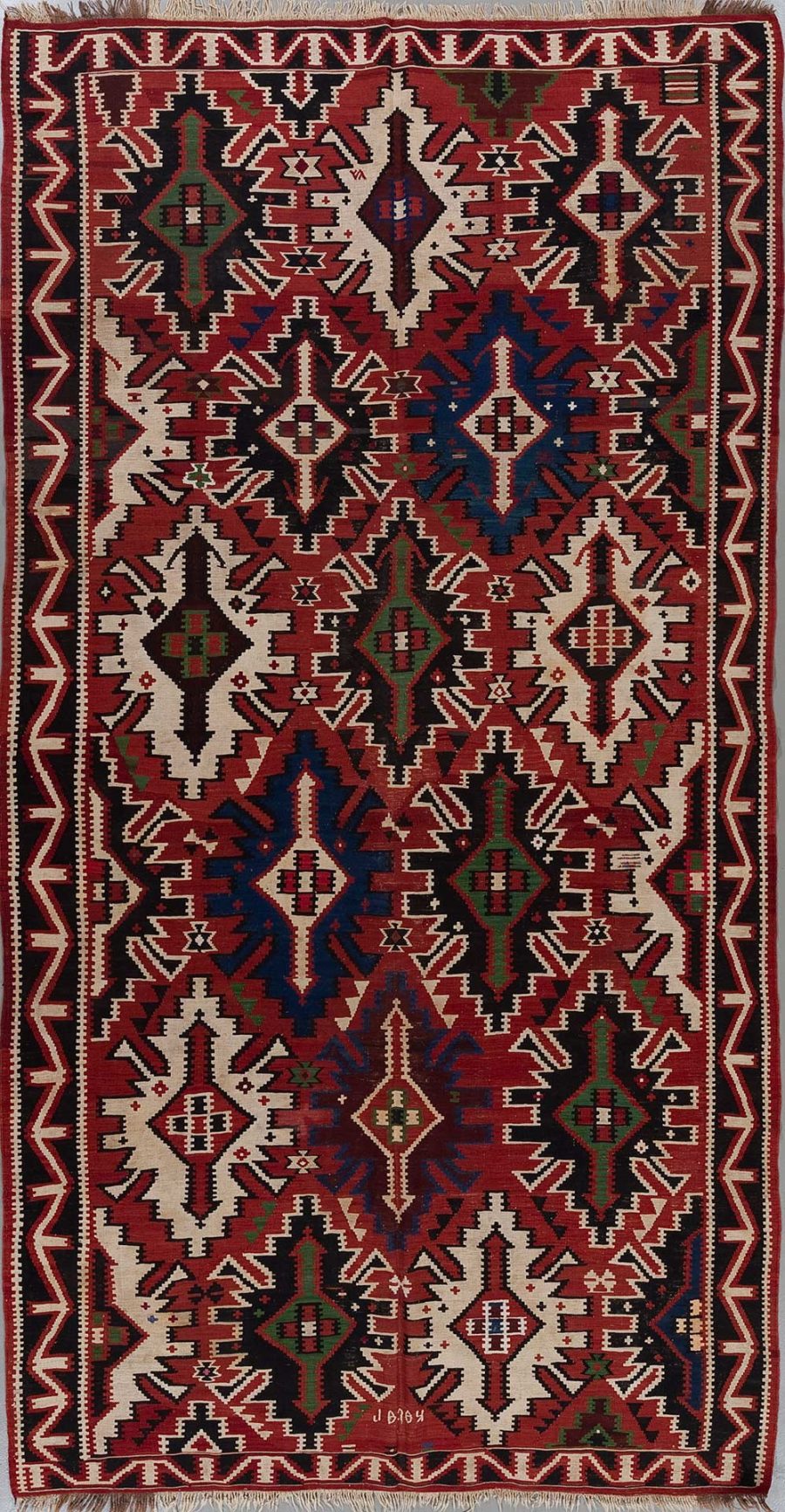 Traditioneller handgewebter Teppich mit komplexen geometrischen Mustern in Rot, Schwarz, Weiß und Blautönen, verziert mit zahlreichen Stern- und Diamantformen, umgeben von einem schmalen Bordürenmuster an den Rändern.
