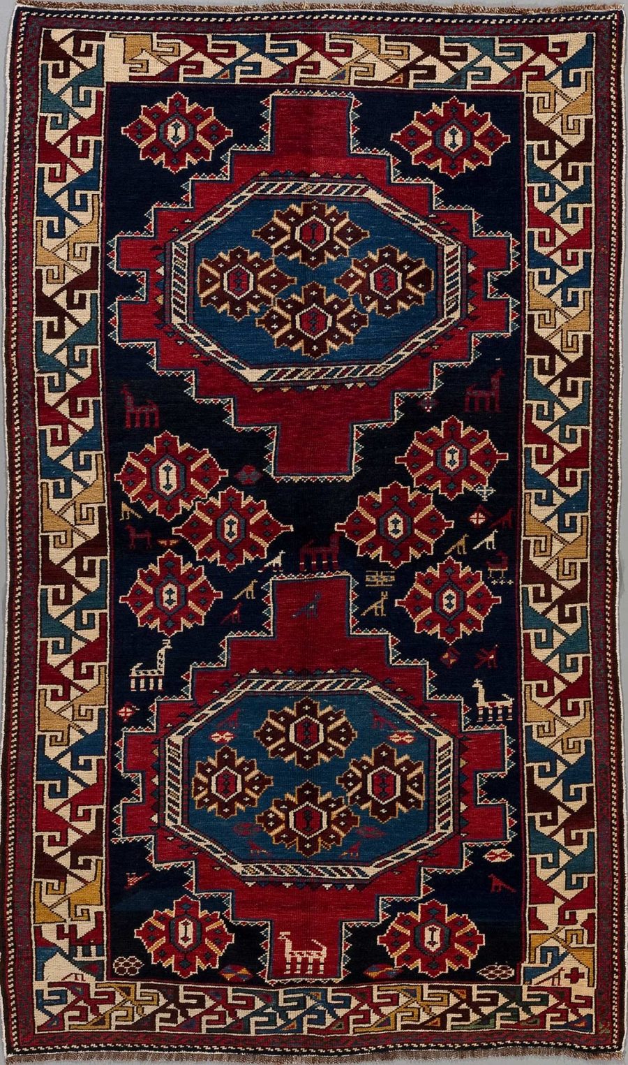 Traditioneller handgeknüpfter Teppich mit zentralem Medaillon-Design, umgeben von geometrischen Mustern und Bordüren in Rot-, Blau-, Beige- und Brauntönen.