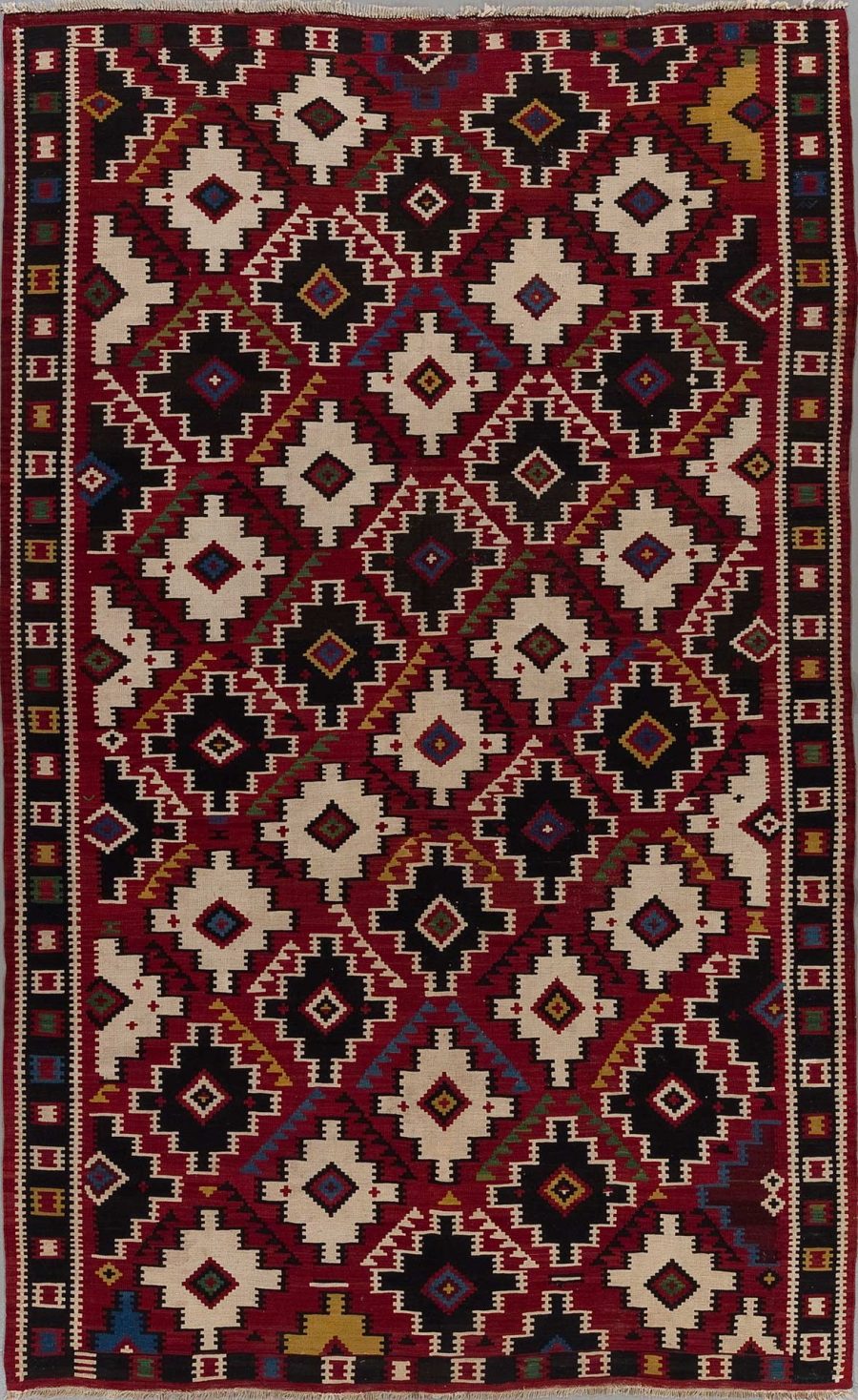 Traditioneller handgewebter Teppich mit komplexem geometrischem Muster in Rot-, Schwarz-, Weiß- und Blautönen.
