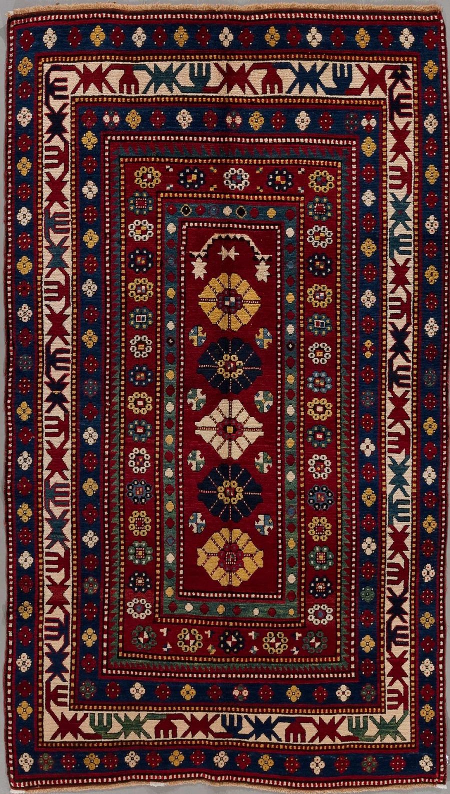 Traditioneller handgeknüpfter Teppich mit komplexen geometrischen und floralen Mustern in Rot, Blau, Beige und anderen Farben, umrandet von dekorativen Bordüren mit Tier- und Pflanzenmotiven.