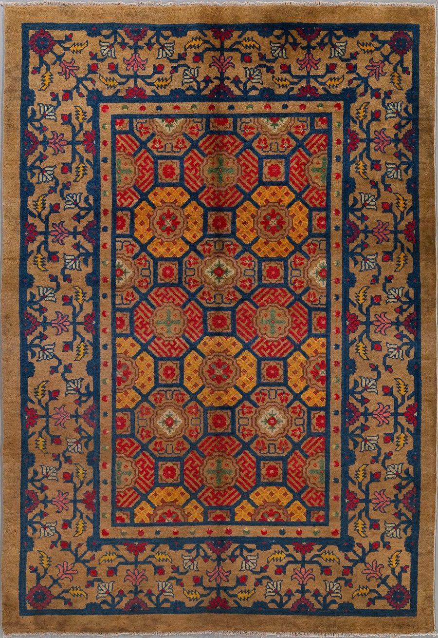 Antik wirkender, handgeknüpfter Teppich mit komplexem, geometrischem Muster in rot, blau, gelb und anderen Farben, umgeben von Bordüren mit floralen Motiven.