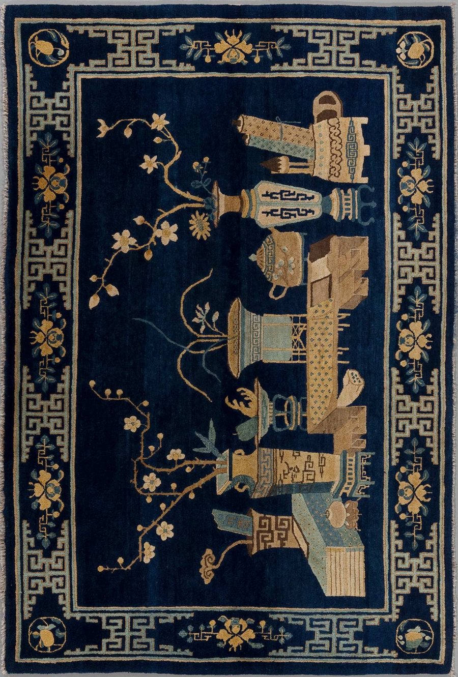 Antiker orientalischer Teppich mit dunkelblauem Hintergrund und traditioneller Verzierung, darunter geometrische Muster und florale Elemente in Beige- und Goldtönen mit einer Grenze im griechischen Schlüsseldesign.