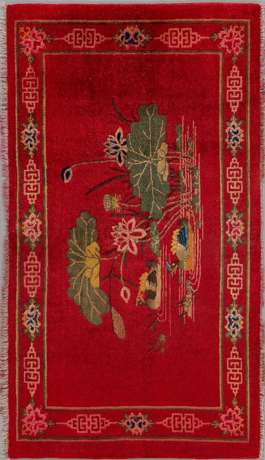 Traditioneller handgeknüpfter Teppich mit einem dichten, blumenartigen Muster auf einem roten Hintergrund, eingerahmt von einem dekorativen geometrischen Rand in beige, blau und roten Tönen.