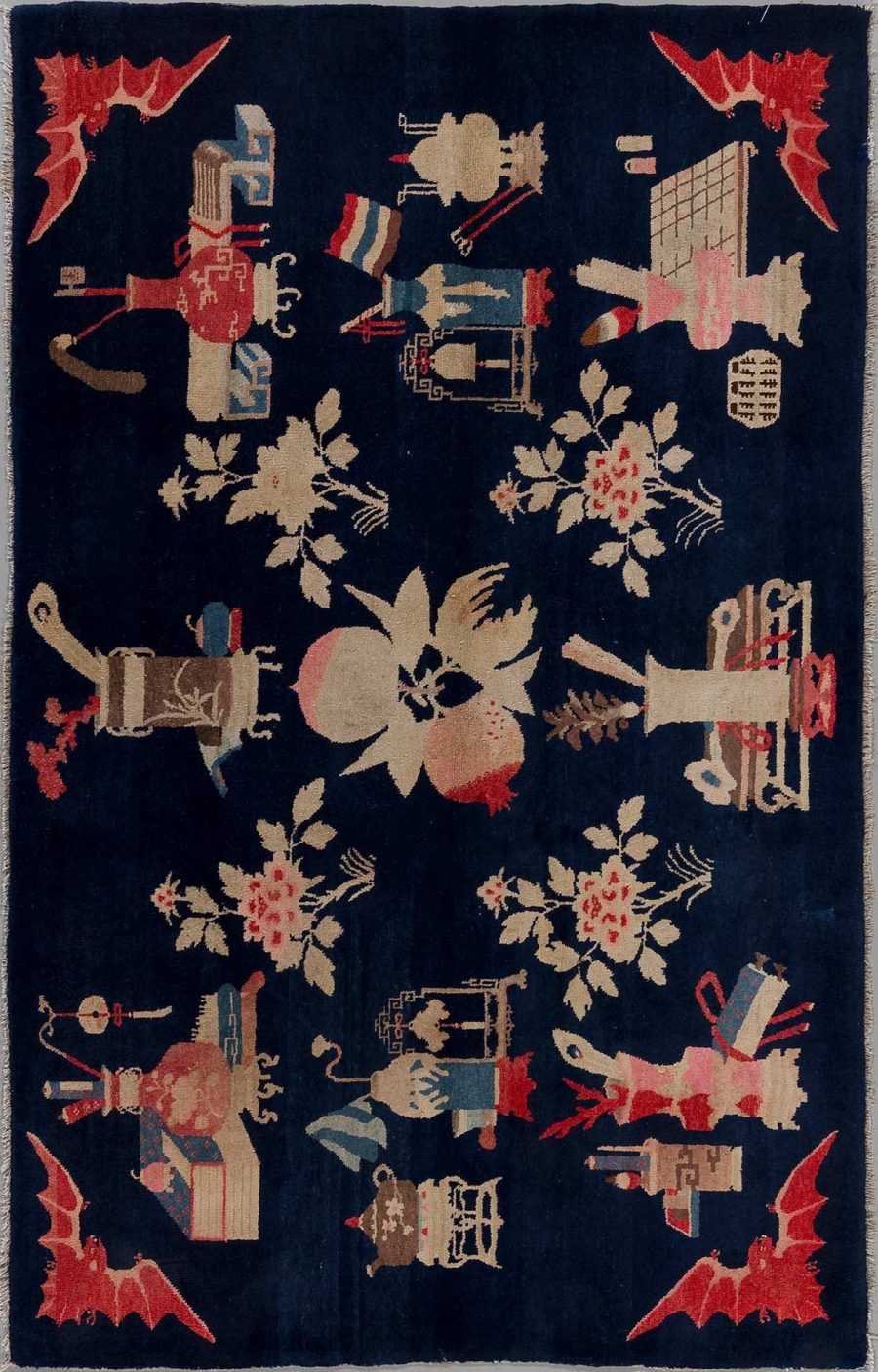 Antiker Teppich mit asiatisch inspirierten Motiven, darunter abstrakte Figuren, Drachen und Blumenmuster, auf dunkelblauem Hintergrund.